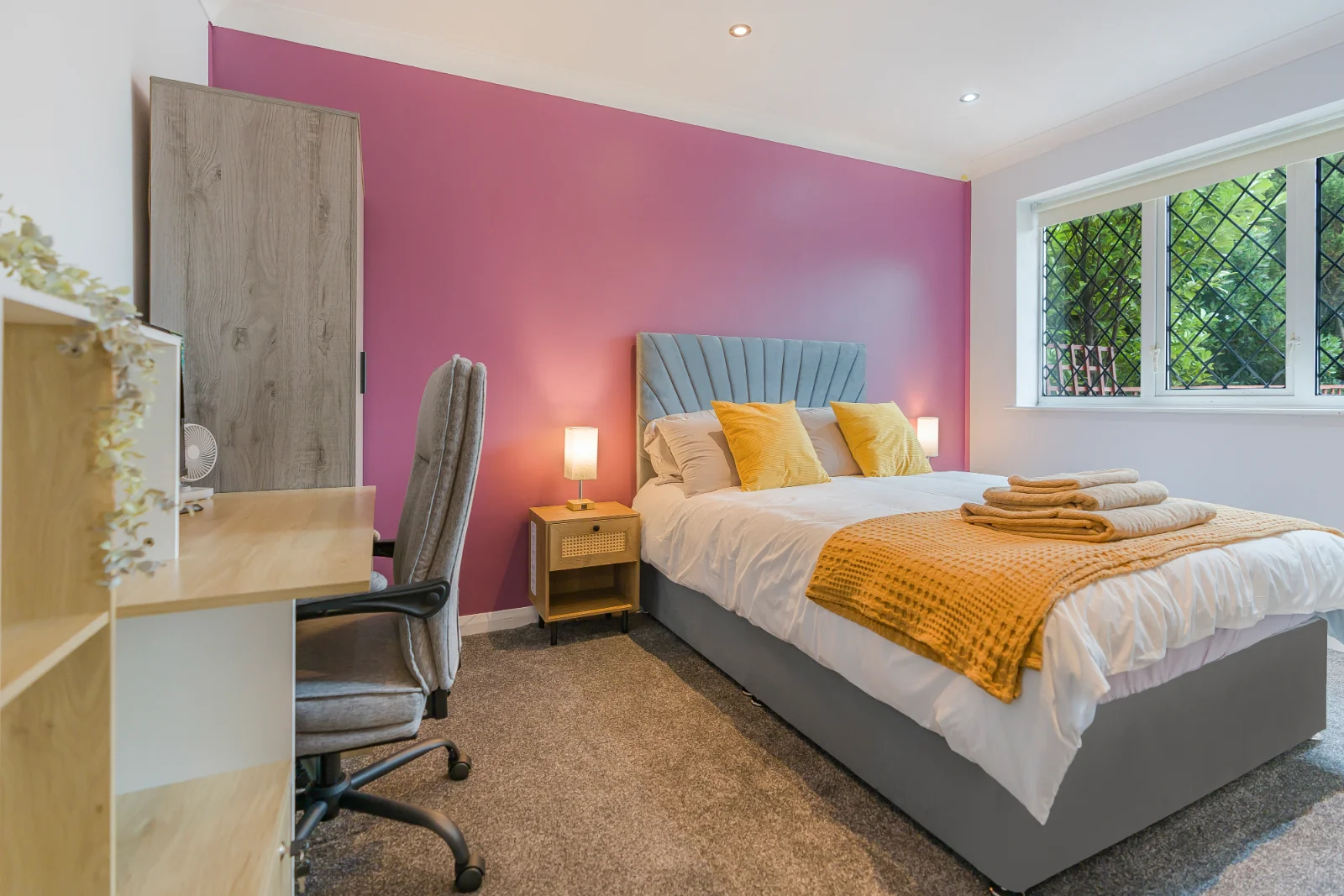 A bright, stylish furnished double bedroom at The Coastal Key in Brighton, with pink feature wall and mustard bedding.